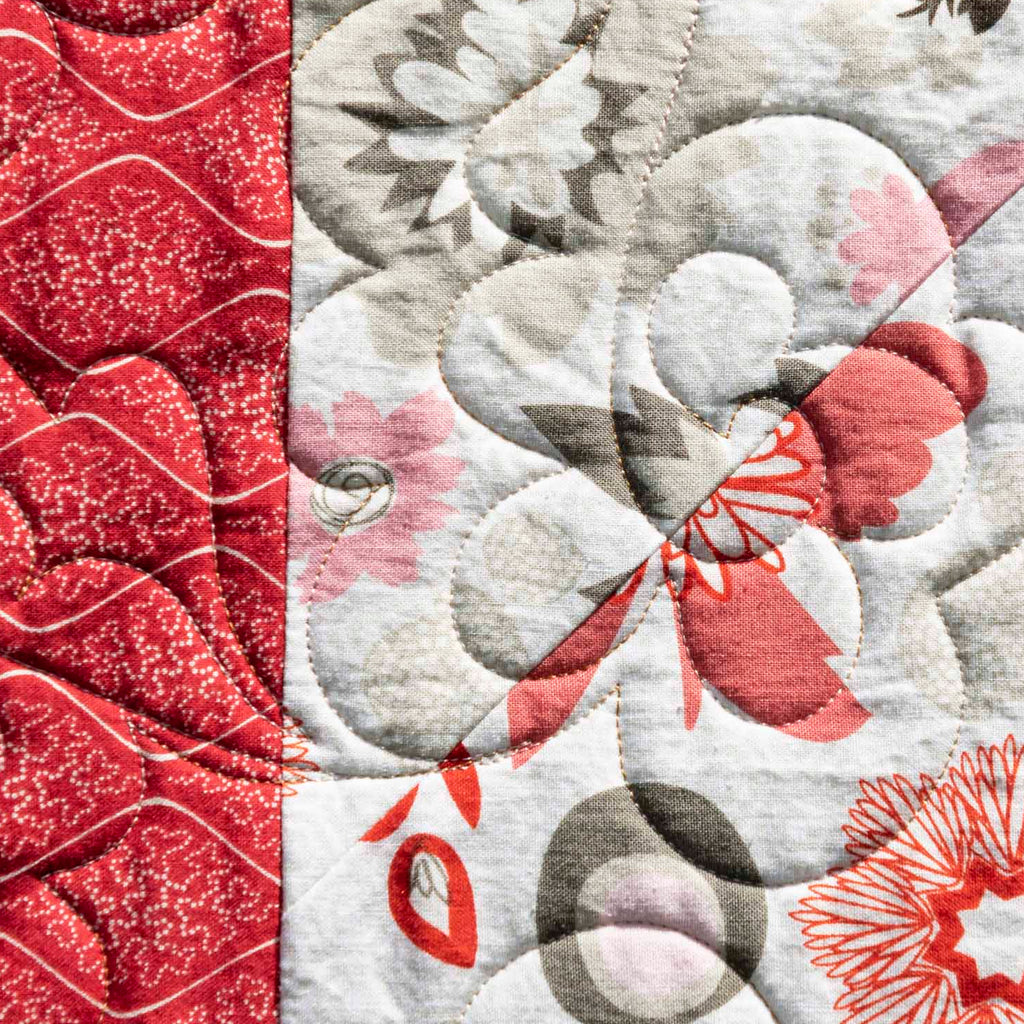 Close-up of a quilt with red, gray, and white patterns