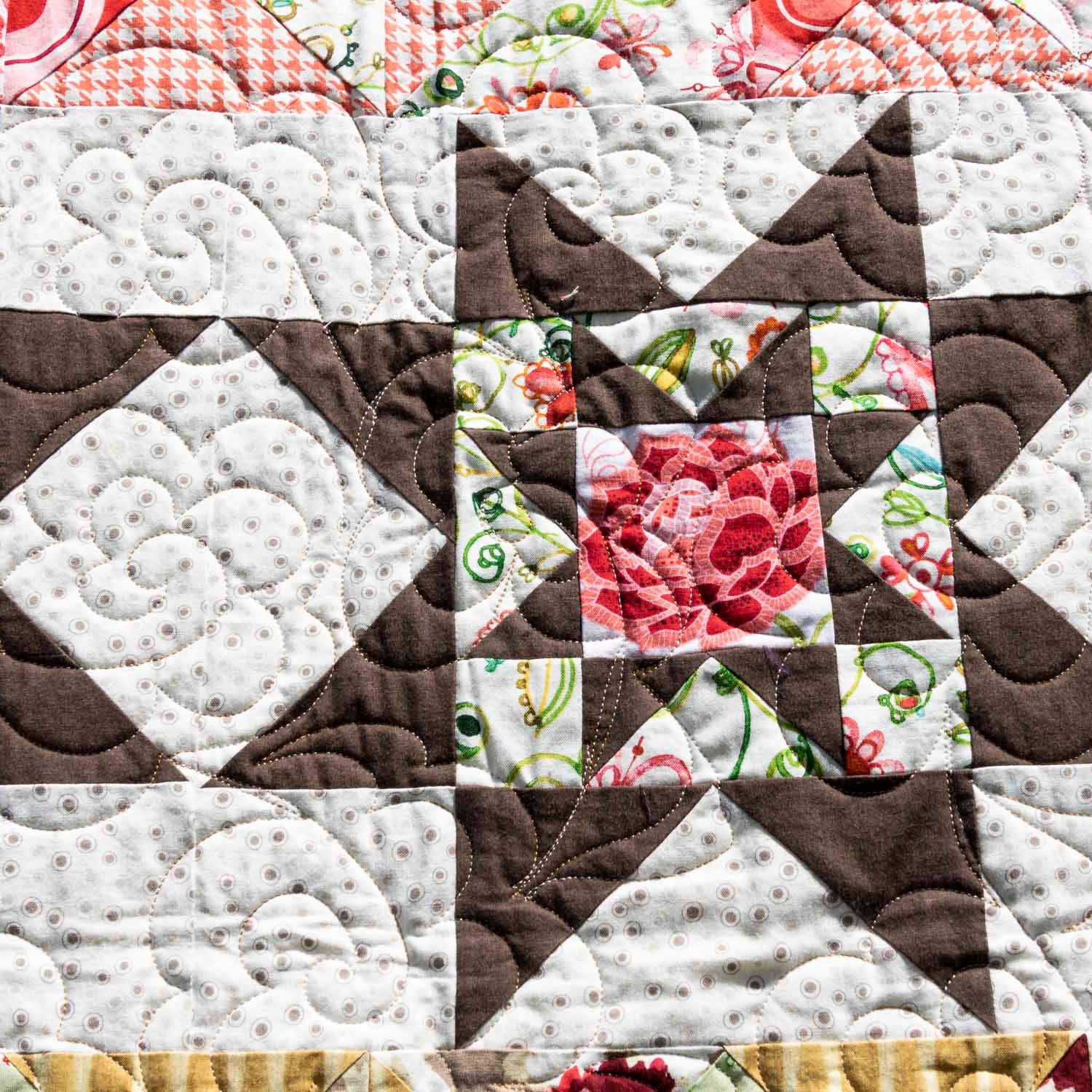 Quilt with floral patterns in brown, white, and pink on a checkered background