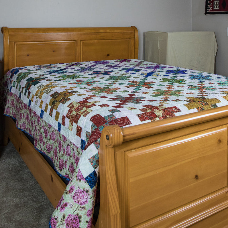 Wooden sleigh bed with a colorful quilt in a bedroom setting.