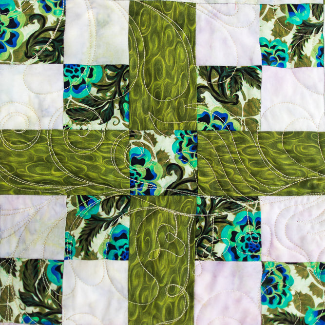 Quilt with green and blue patterned squares on a white background