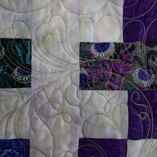 Close-up of a quilt with floral patterns and white stitching