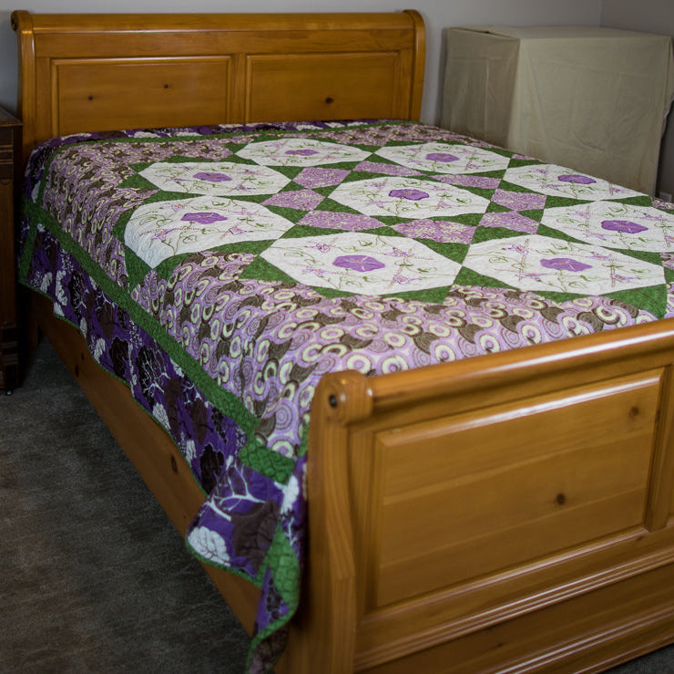 Purple and green floral checkered quilt laid out on a bed