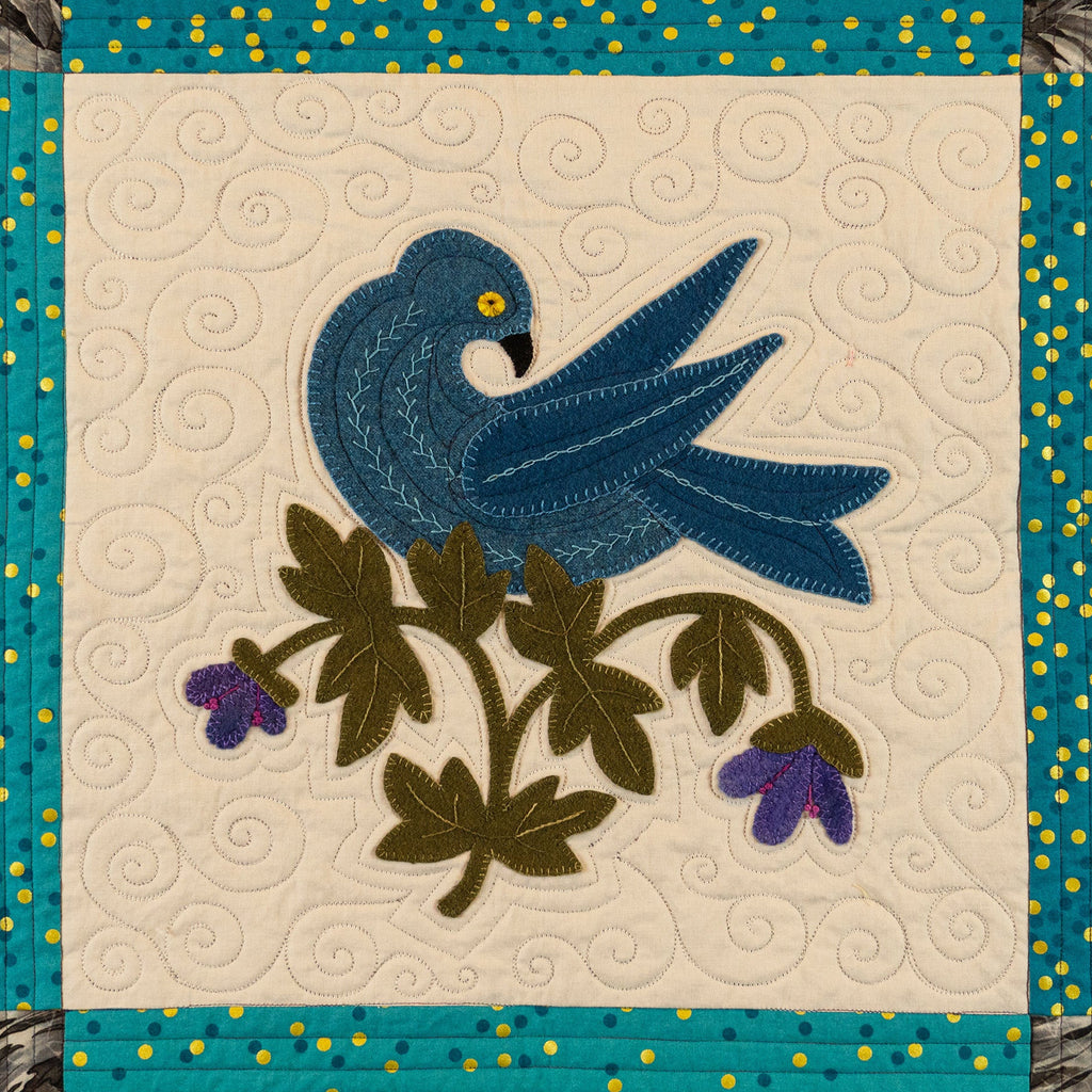 Quilt block with blue bird and floral design on a beige background