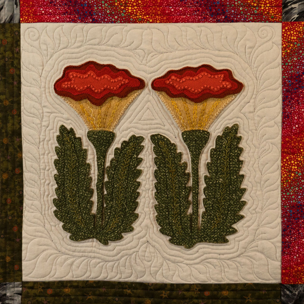Quilt block with red flowers and green leaves on a textured background