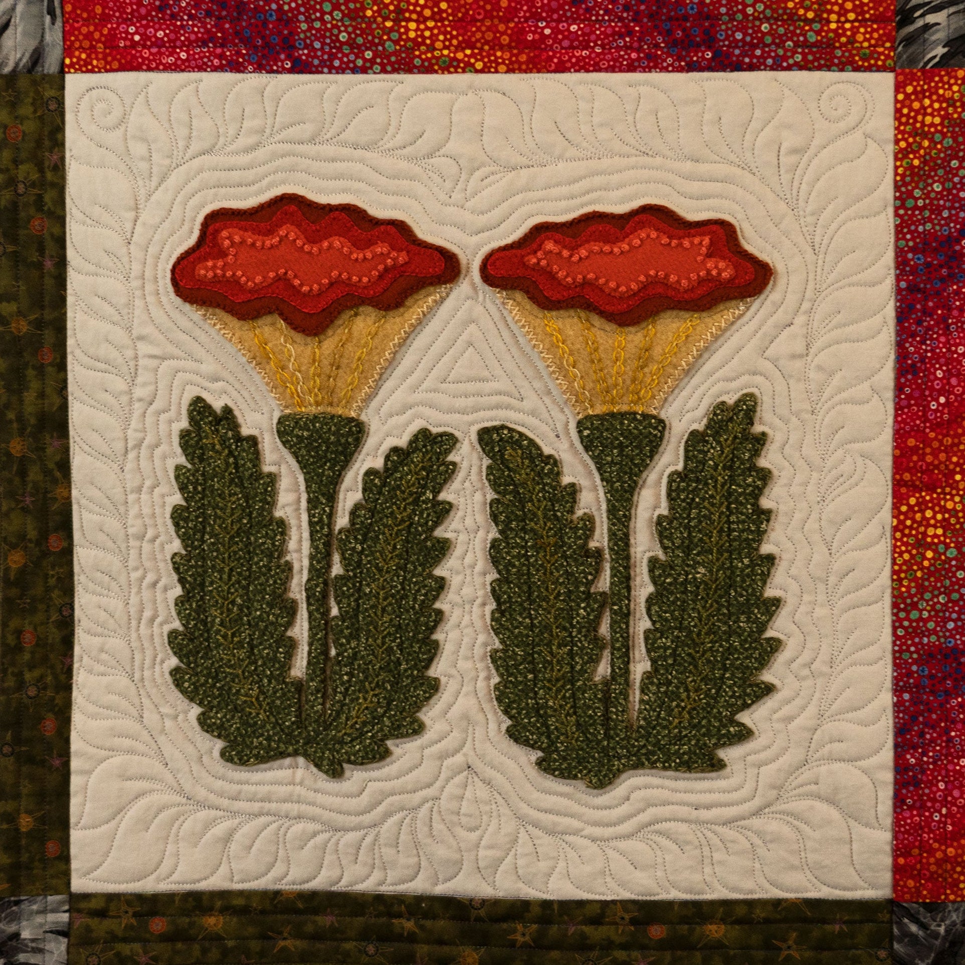 Quilt block with red flowers and green leaves on a textured background