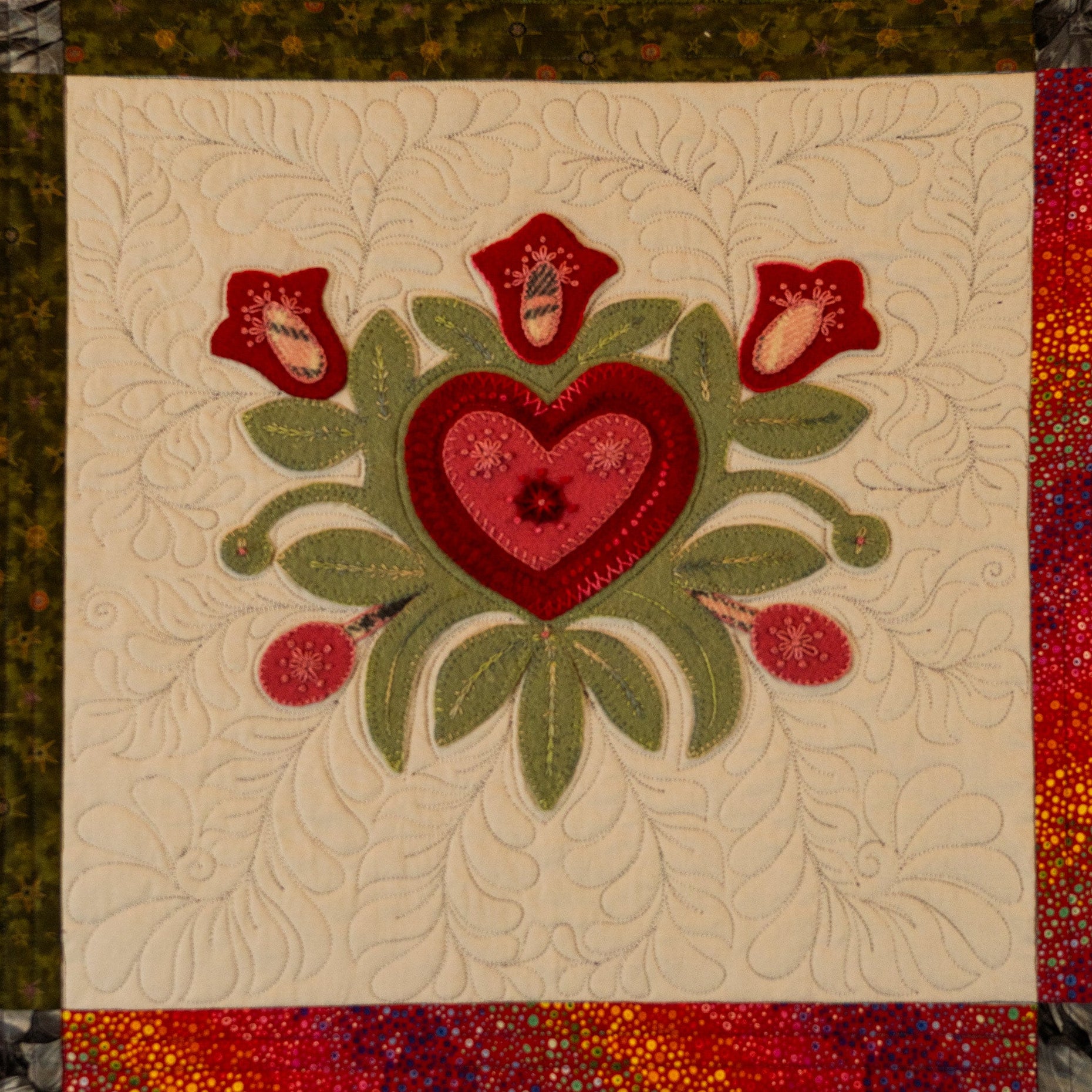 Quilt block with a red heart and floral design on a beige background