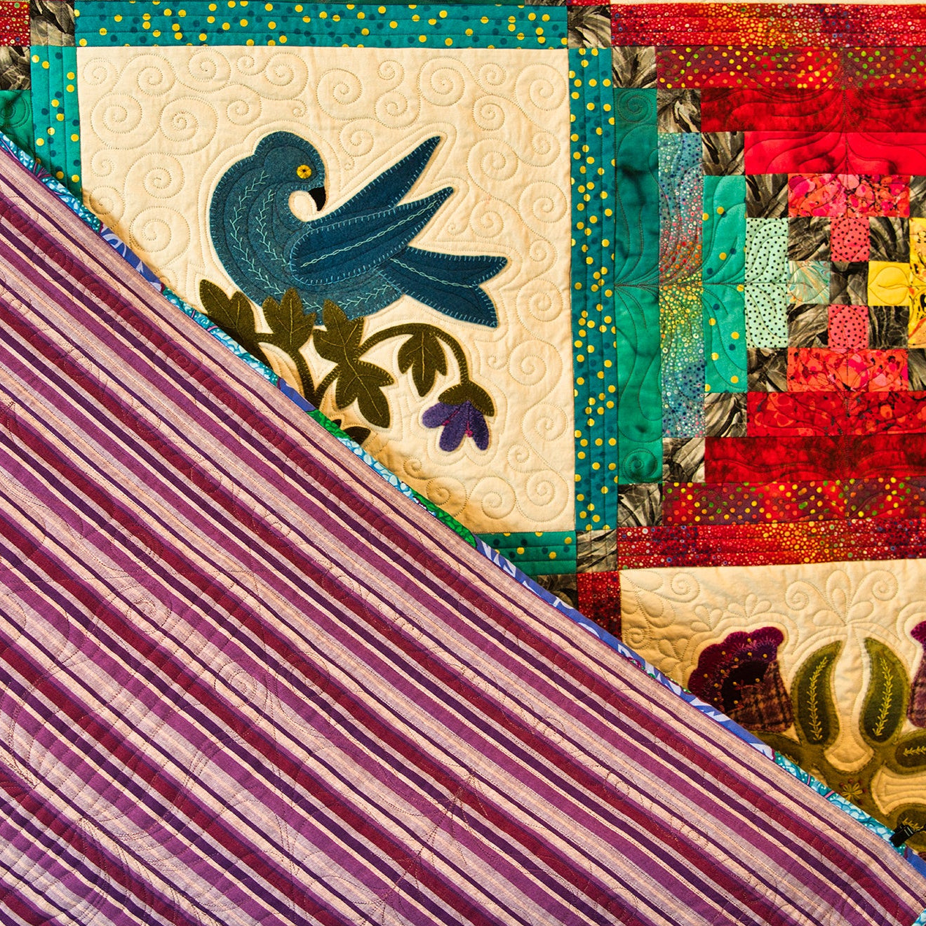 Close-up of a colorful quilt with a bird design and striped fabric.