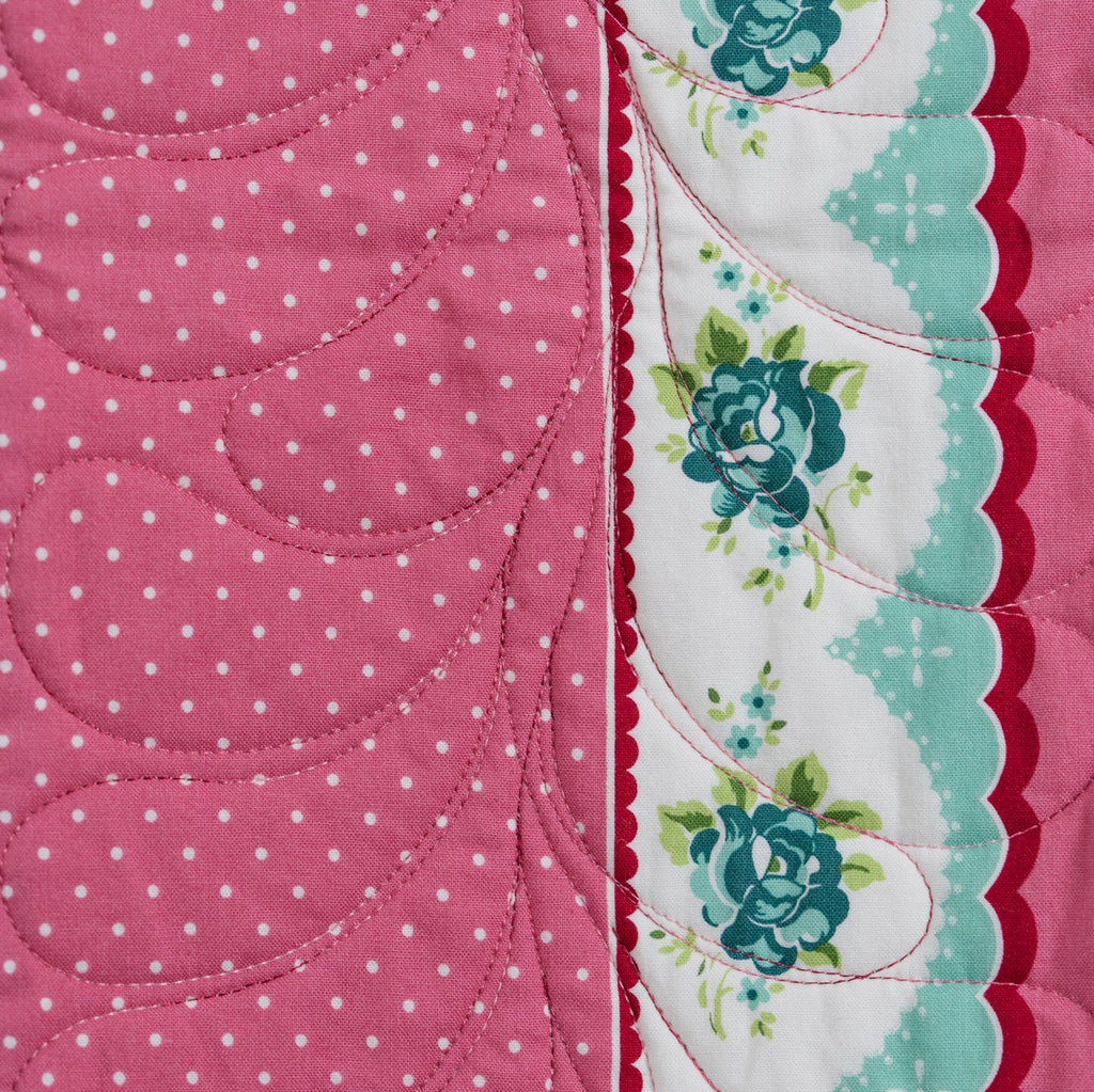 Quilt with floral and polka dot patterns on a pink background