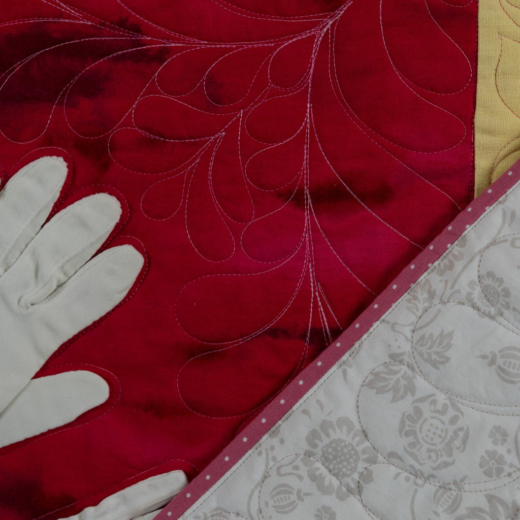 Close-up of a red fabric with white gloves and a textured gray surface.