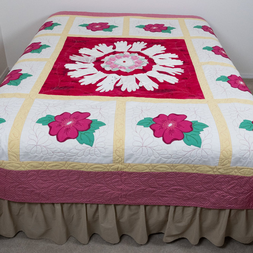 Quilt with floral patterns on a bed against a white wall