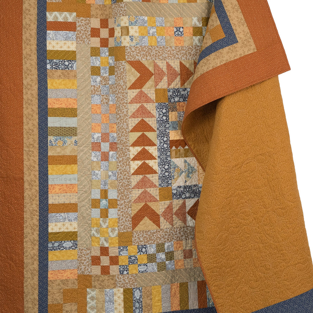 Quilt with geometric pattern in orange, blue, and yellow on a white background