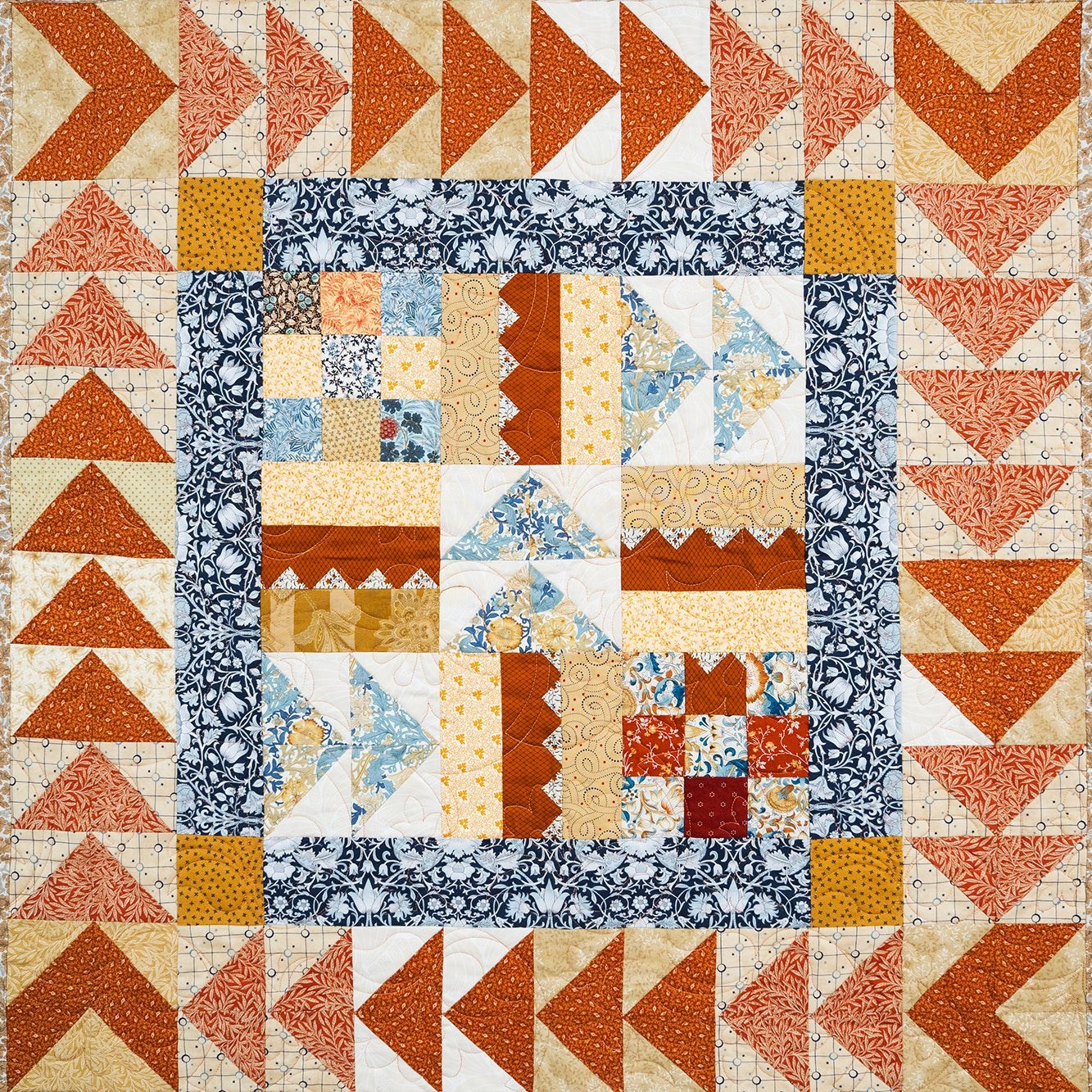 Quilt with geometric pattern featuring triangles and squares in various colors.
