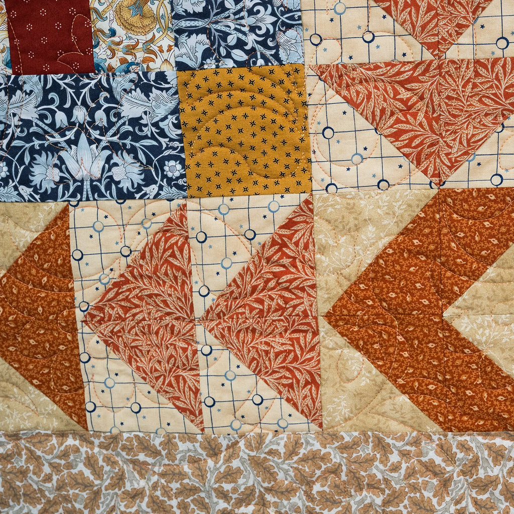 Quilt with various patterns and colors including red, blue, and beige.