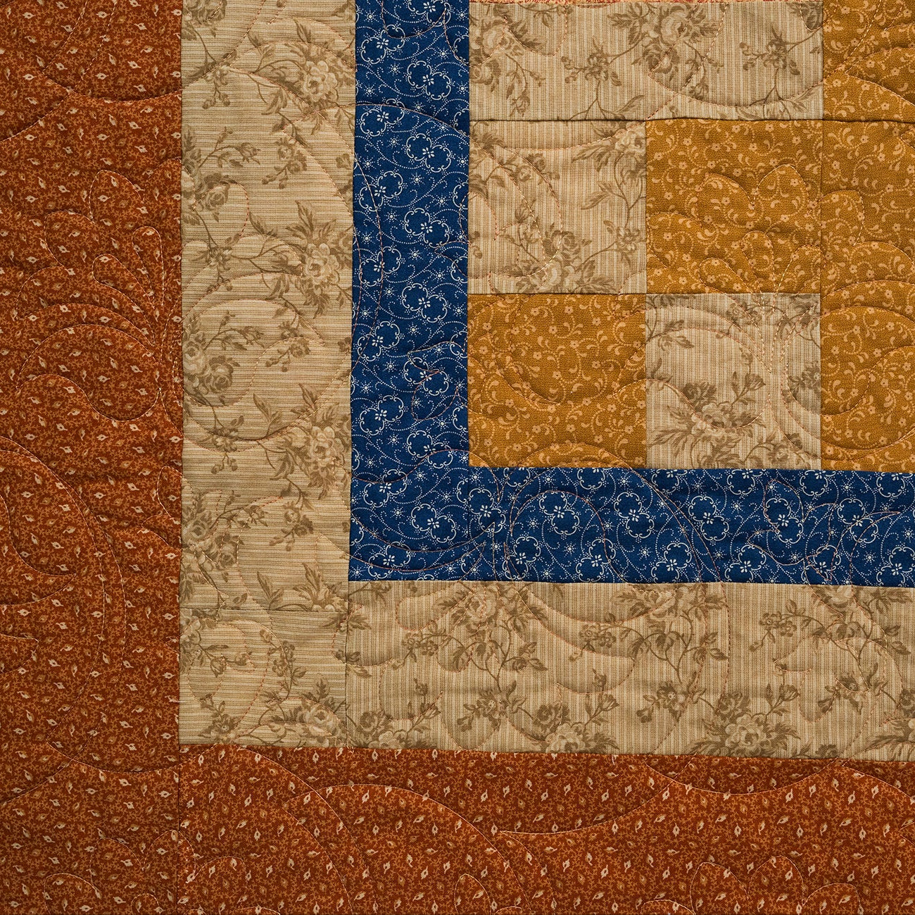 Close-up of a quilt with brown, blue, and beige patterns