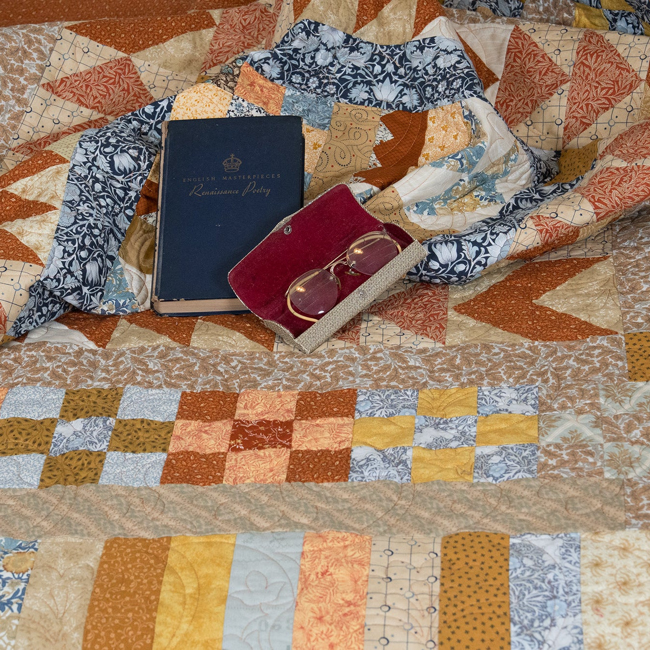 Quilt with books and glasses on a patterned surface