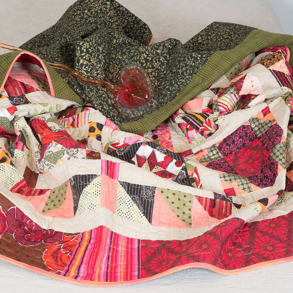 Quilt with floral and patchwork patterns draped over a surface