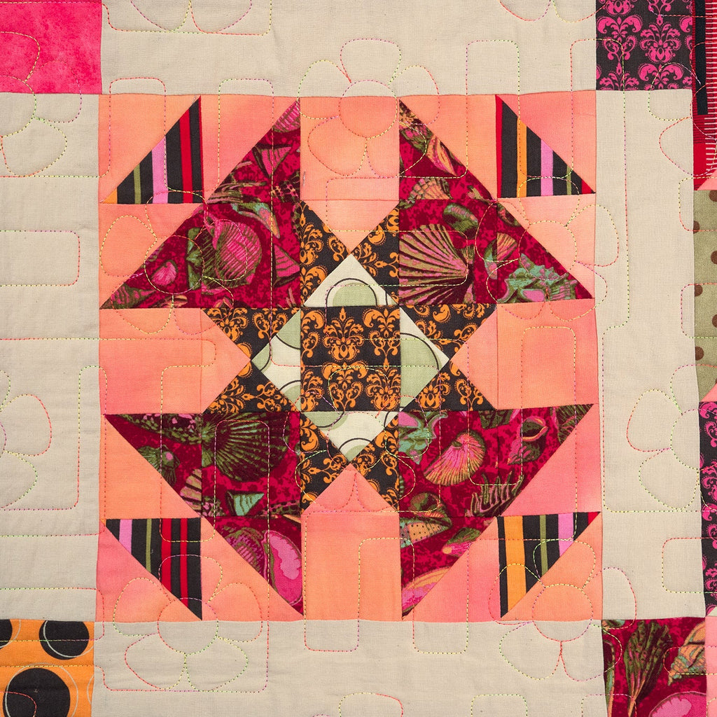 Quilt with geometric pattern featuring pink, orange, and black colors on a beige background.