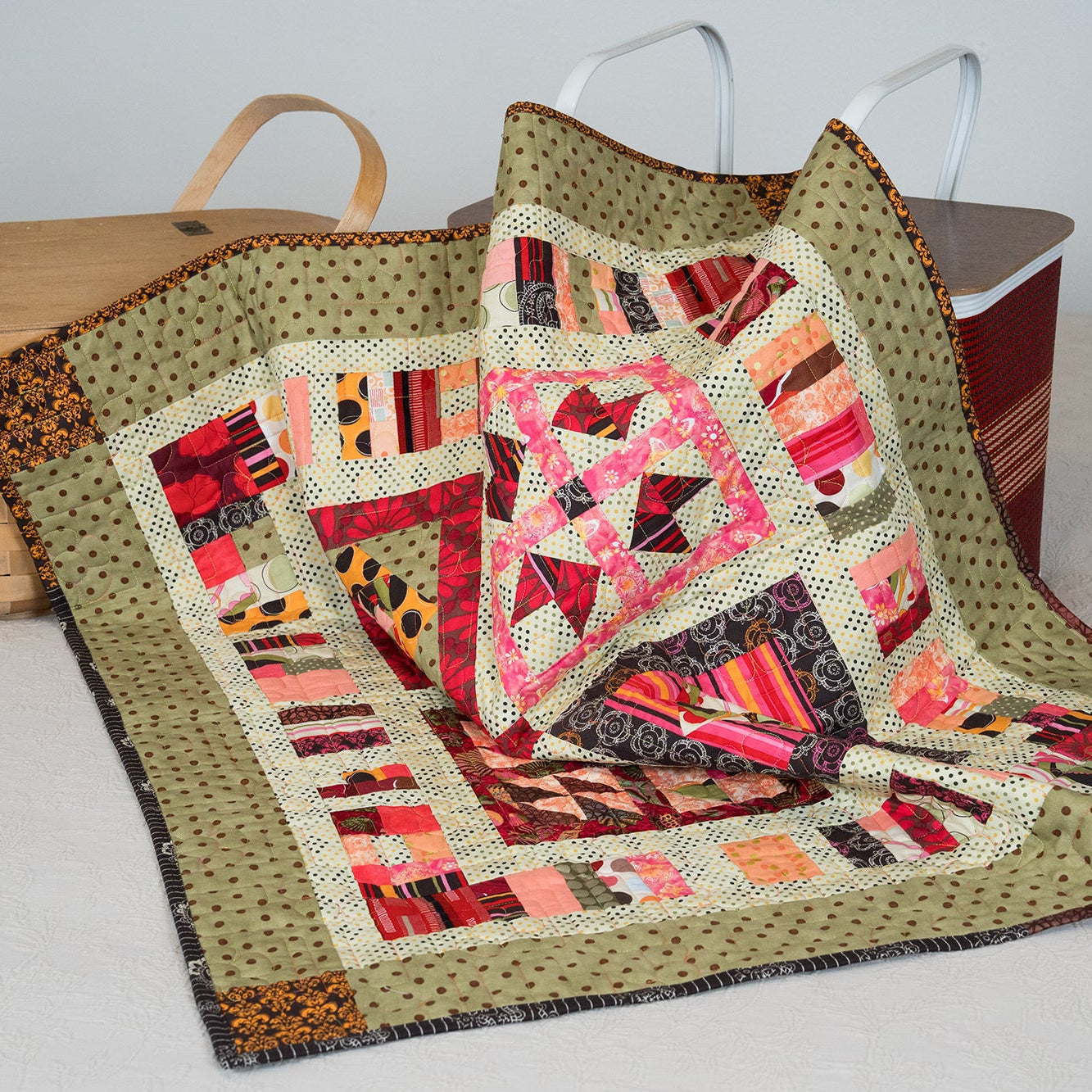Colorful quilt with geometric pattern on a white surface, with baskets in the background.