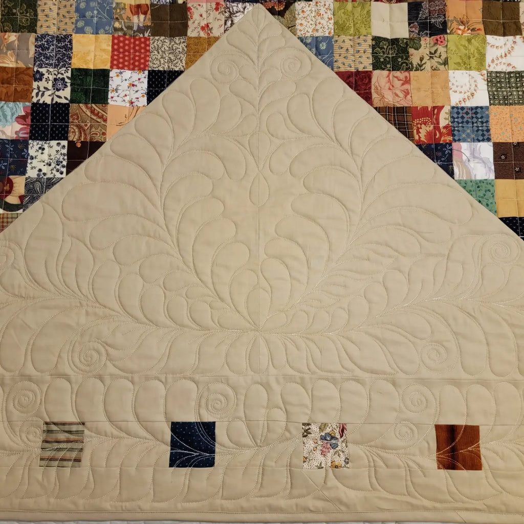 Beige quilt with intricate patterns on a colorful patchwork background