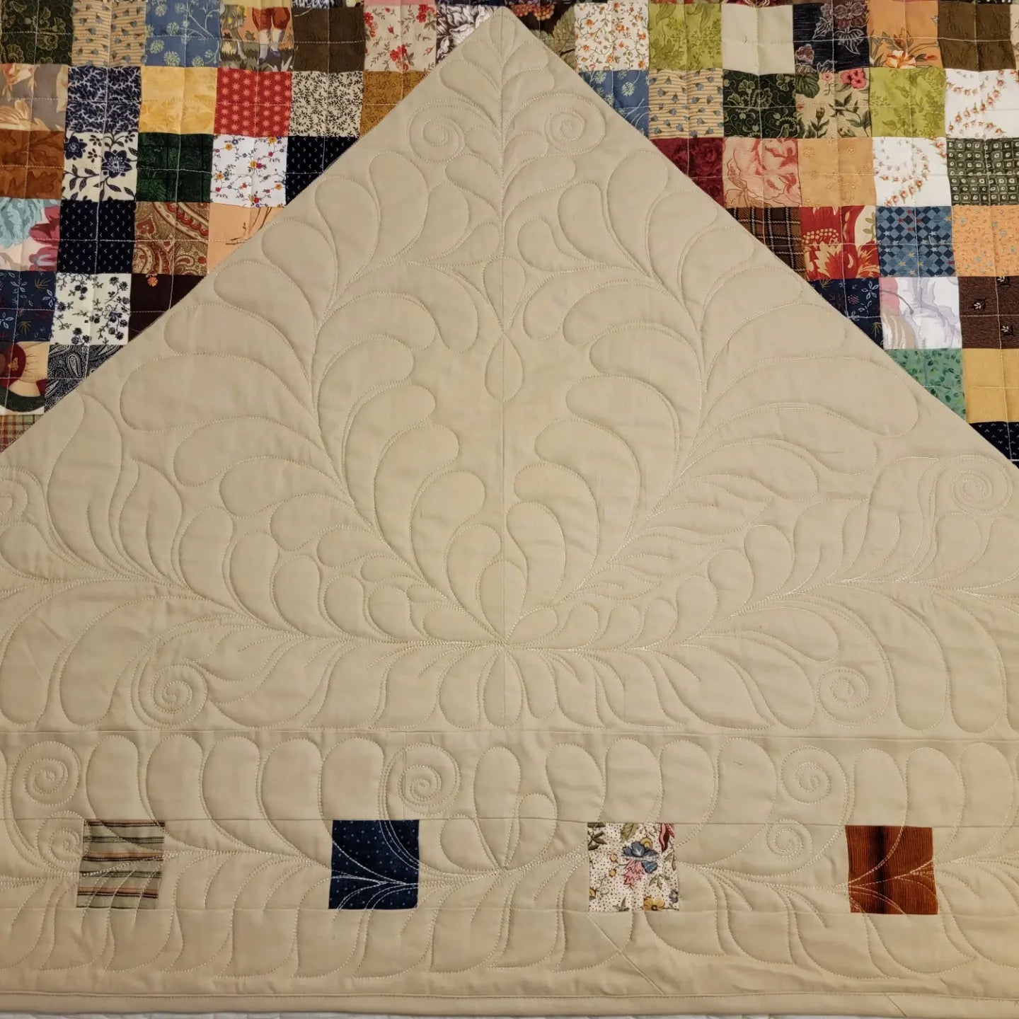 Beige quilt with intricate patterns on a colorful patchwork background