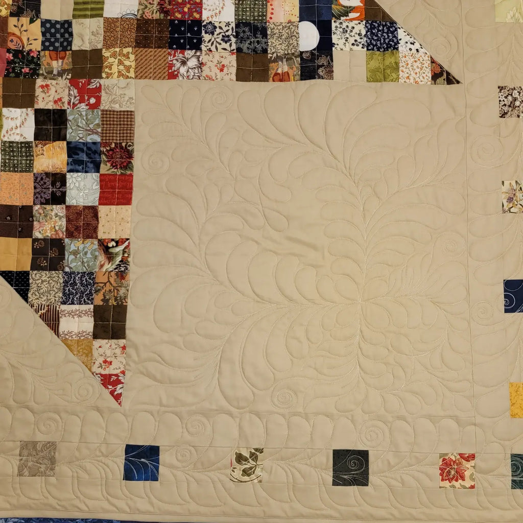 Patchwork quilt with a beige background and colorful square patterns.