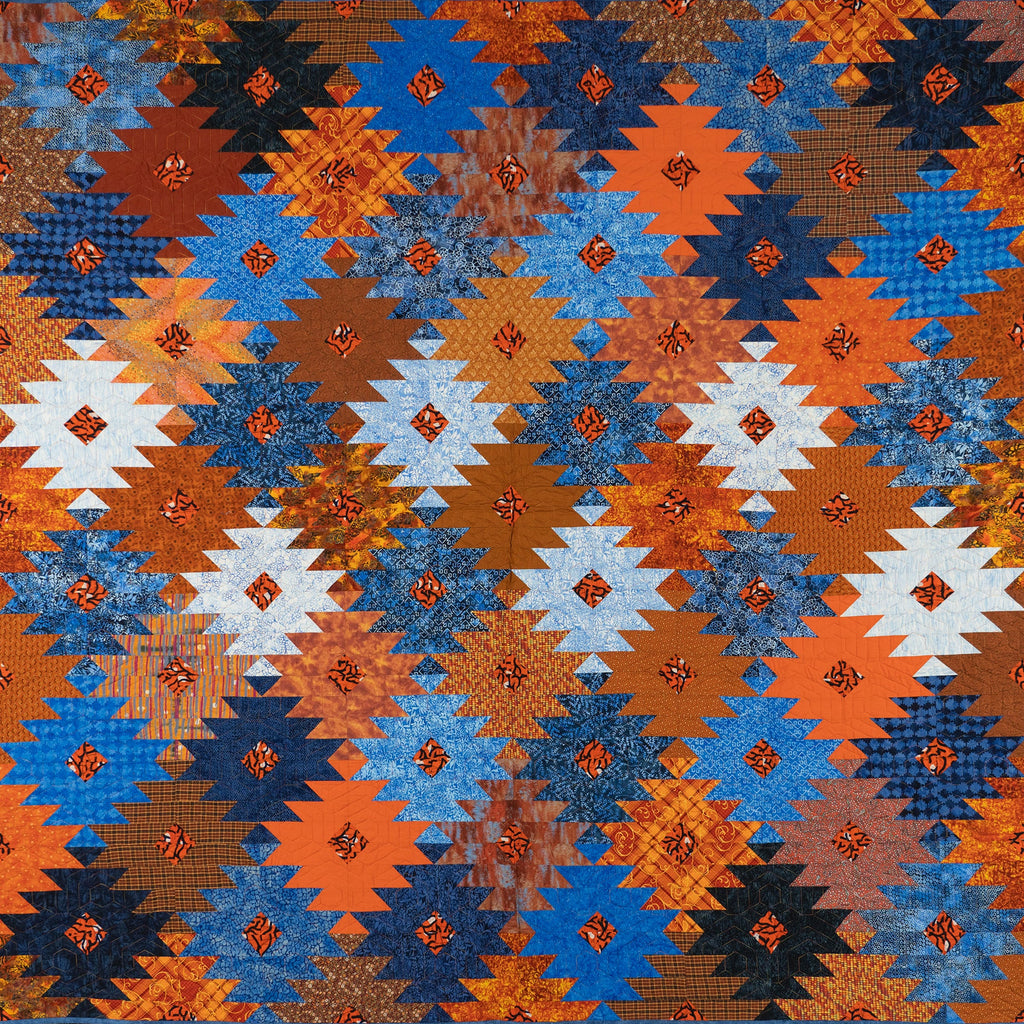 Orange and blue ikat print quilt in a honeycomb print.
