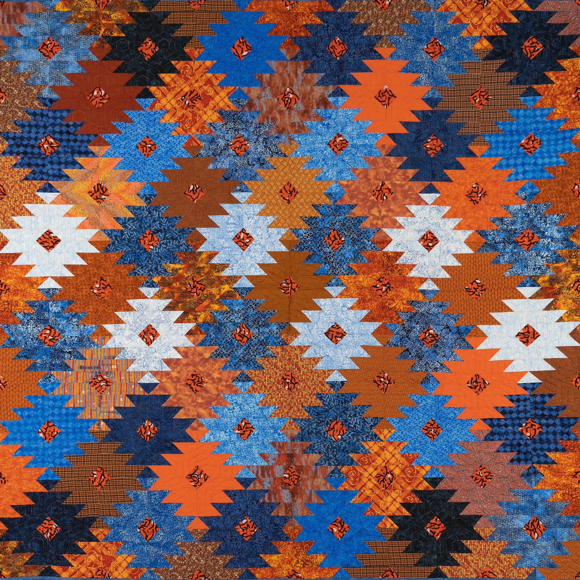Orange and blue ikat print quilt in a honeycomb print.