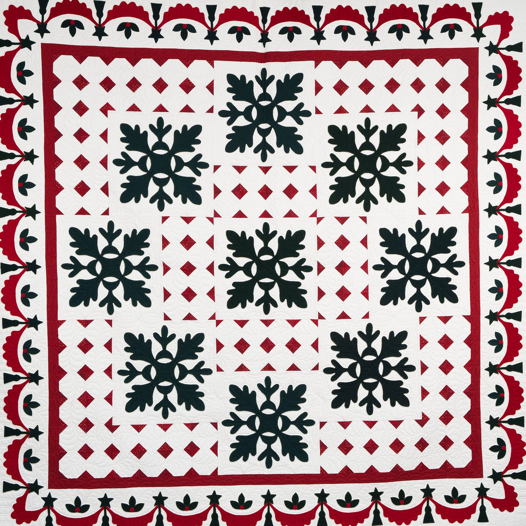 Quilt with black snowflake pattern on a white background, bordered by red and black geometric designs.