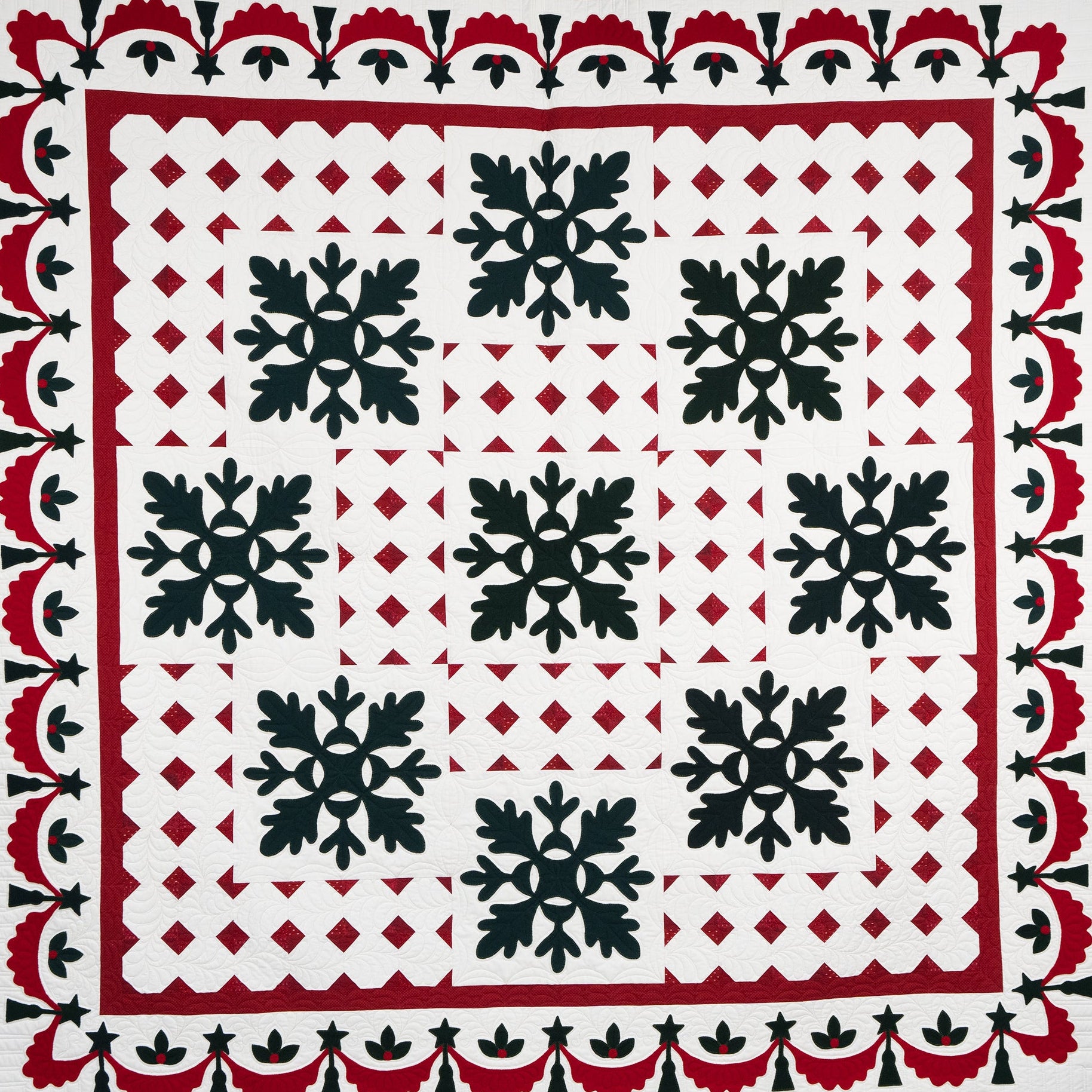 Quilt with black snowflake pattern on a white background, bordered by red and black geometric designs.