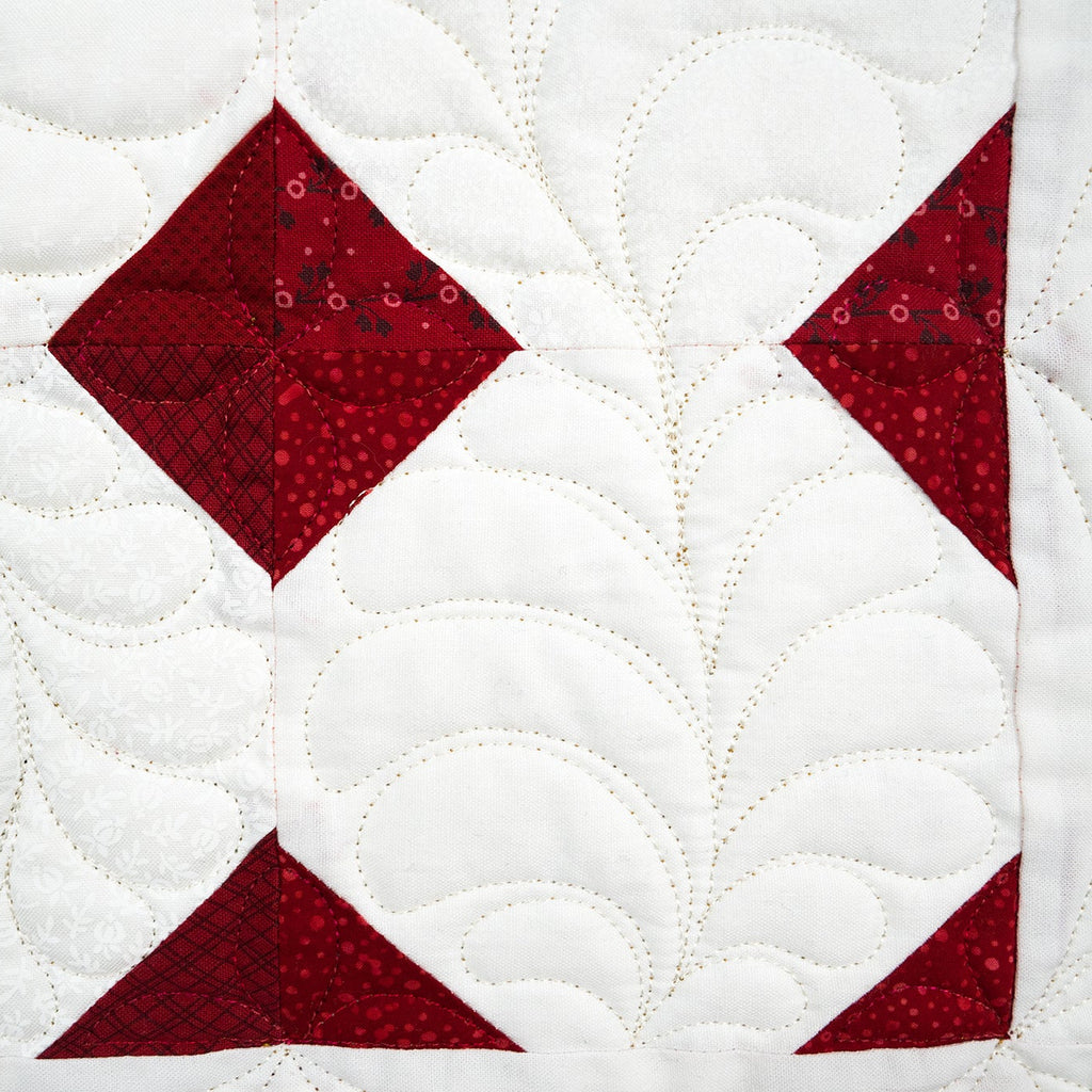 Quilt with red diamond pattern on a white background