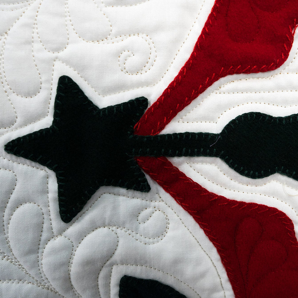 Close-up of a quilt with star and bow design on a white background