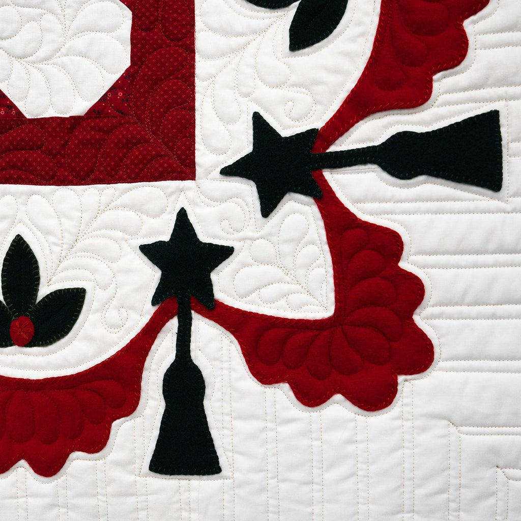 Quilt with red, white, and black star and floral patterns on a white background