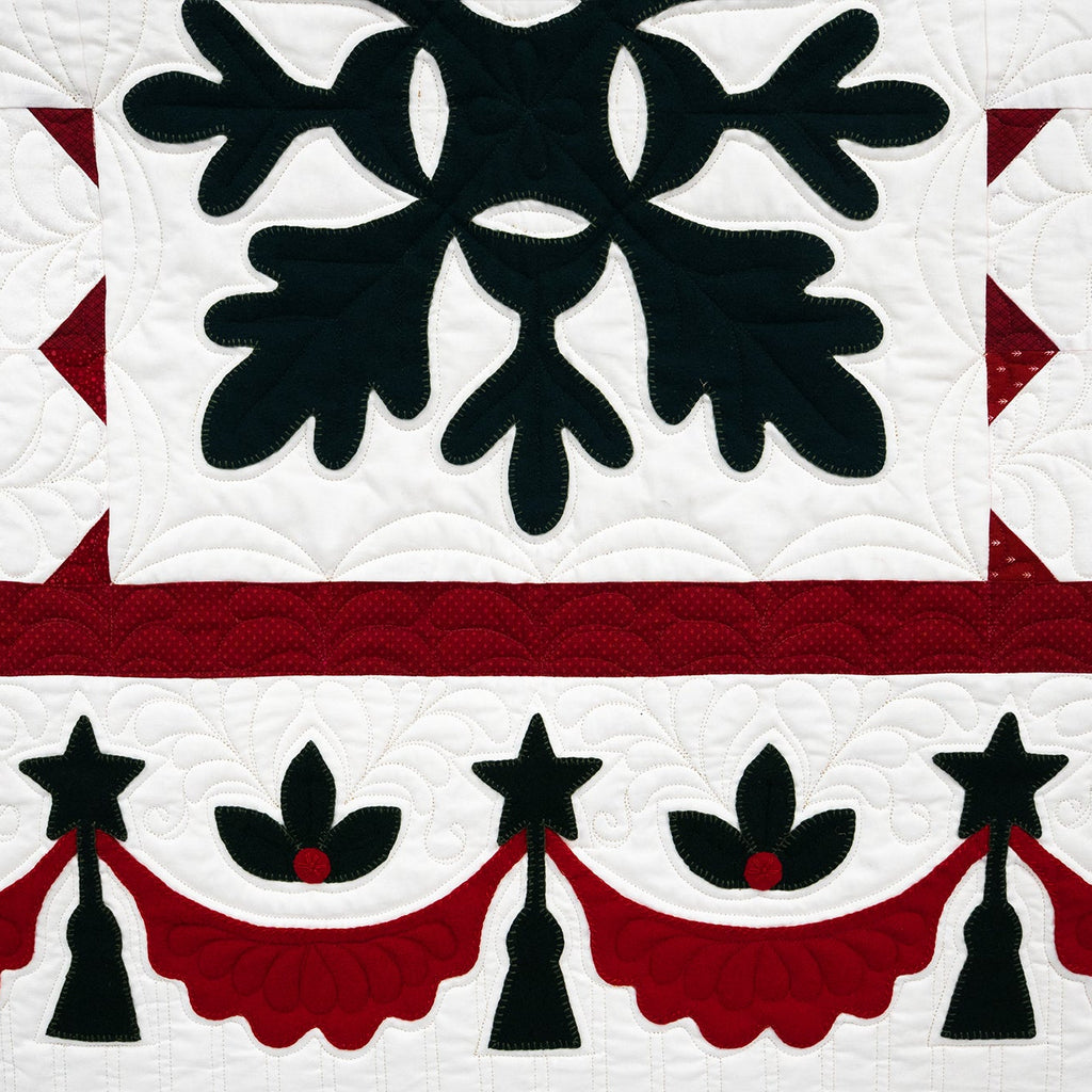 Quilt with black floral design on a white background, bordered by red and black patterns.