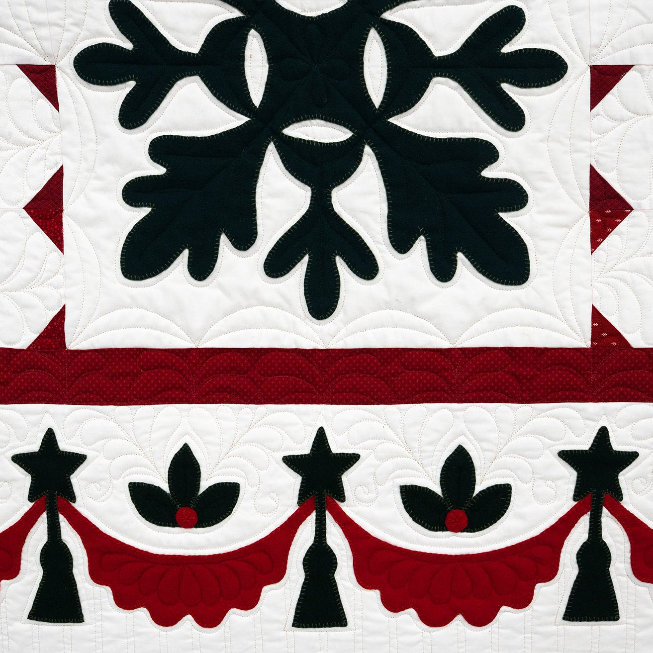Quilt with black floral design on a white background, bordered by red and black patterns.