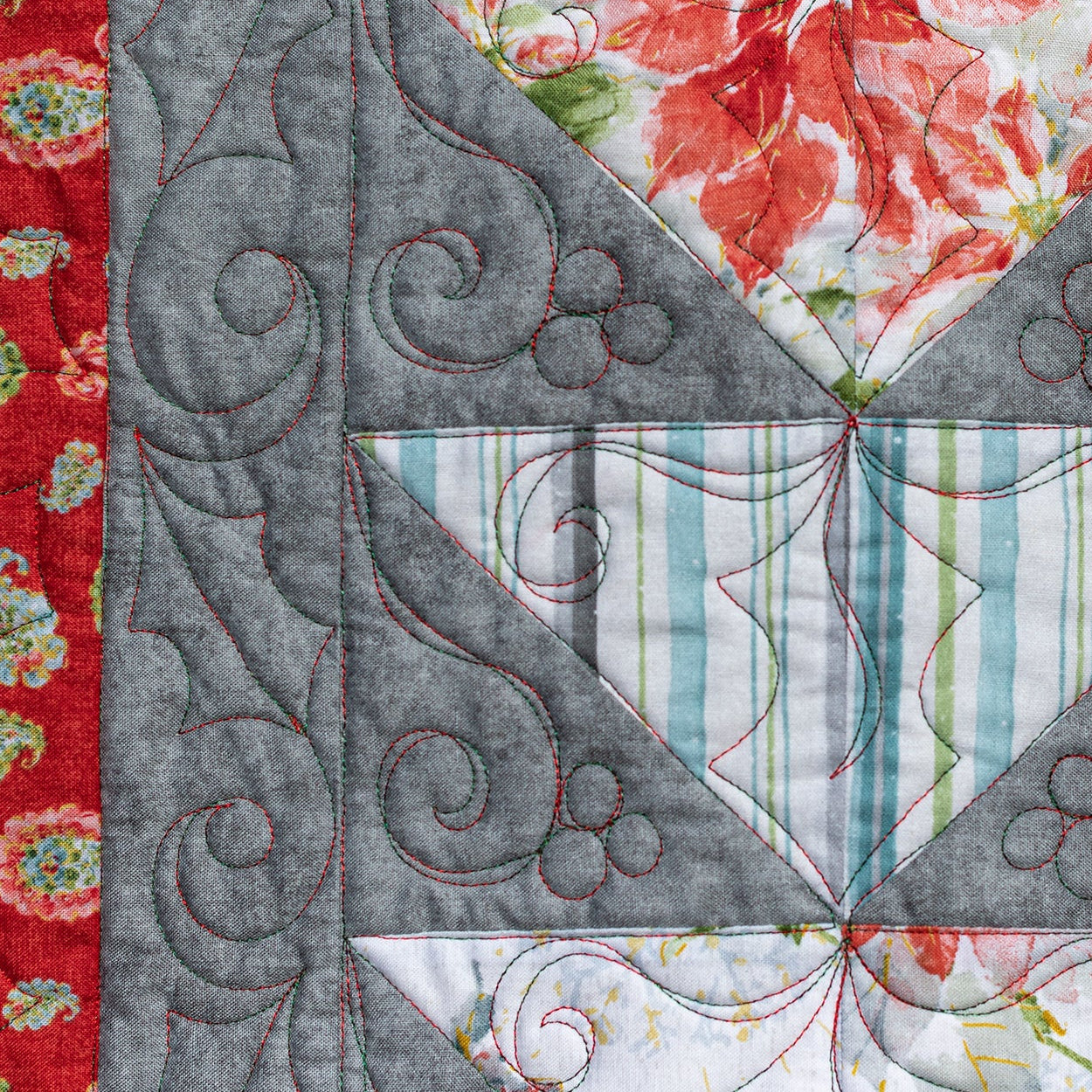 Quilt with geometric pattern and floral accents on a red background