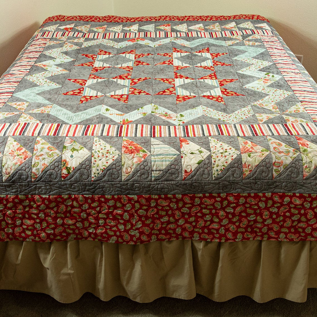Quilt with geometric pattern on a bed in a room.