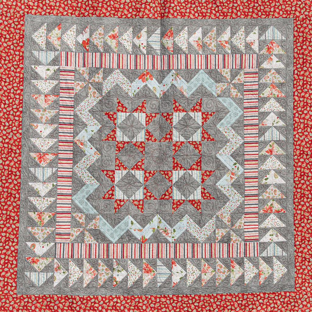 Quilt with geometric pattern on a red floral border
