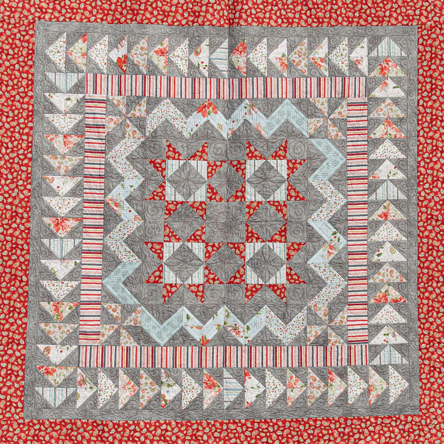 Quilt with geometric pattern on a red floral border
