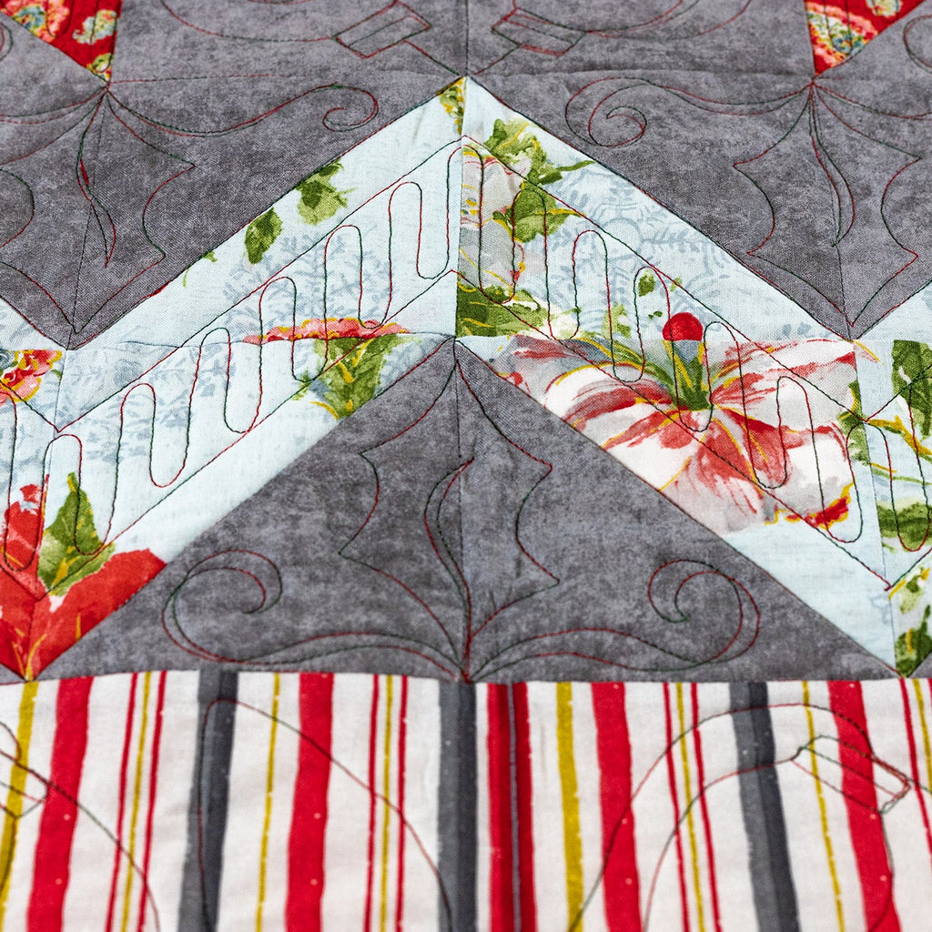 Quilt with geometric pattern featuring gray, red, green, and white colors.