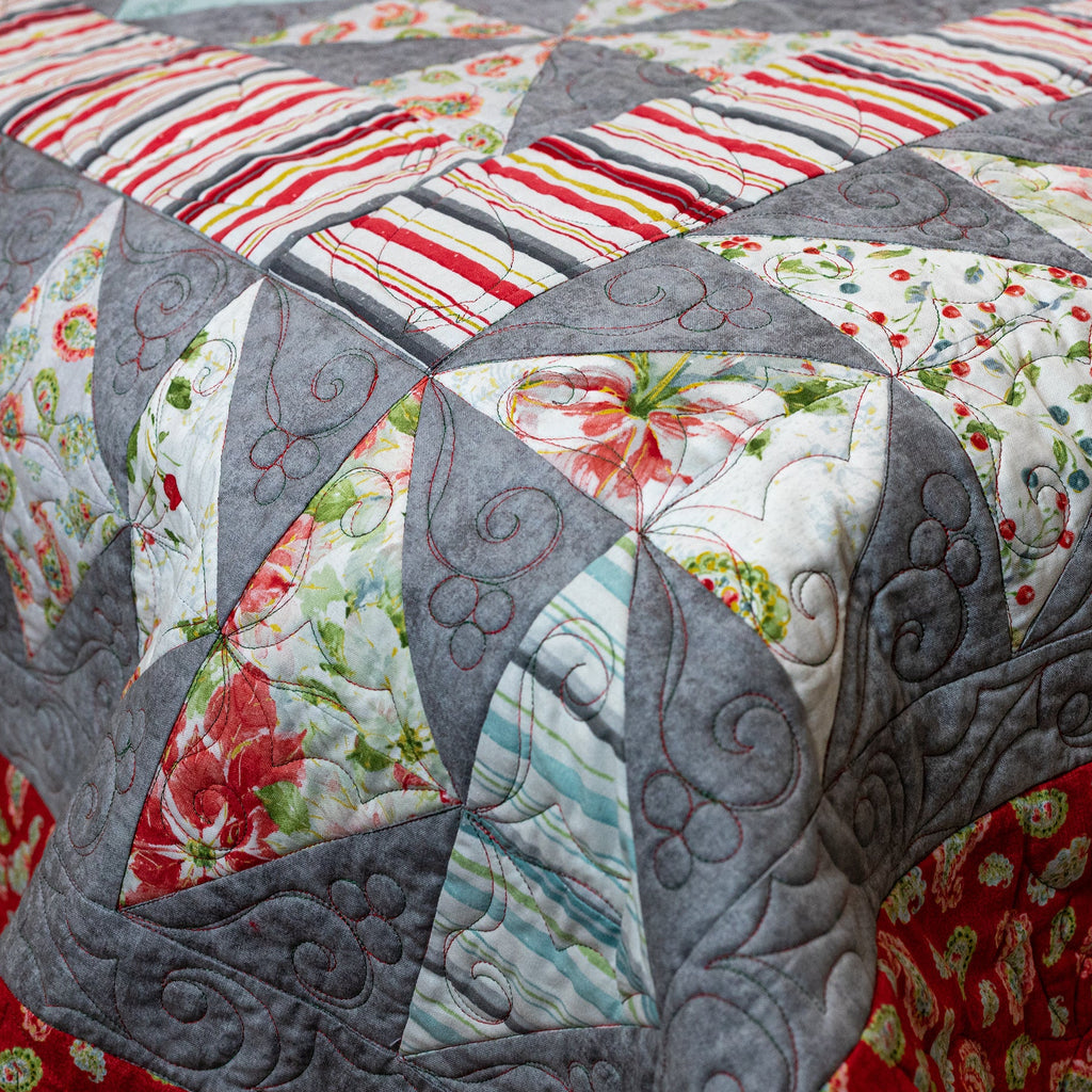 Quilt with geometric pattern featuring floral and striped designs.