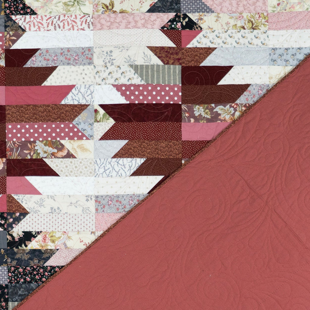 A quilted fabric panel with a geometric patchwork design in dusty pink, burgundy, brown, cream, and floral prints, with a solid dusty rose section in the lower right corner.