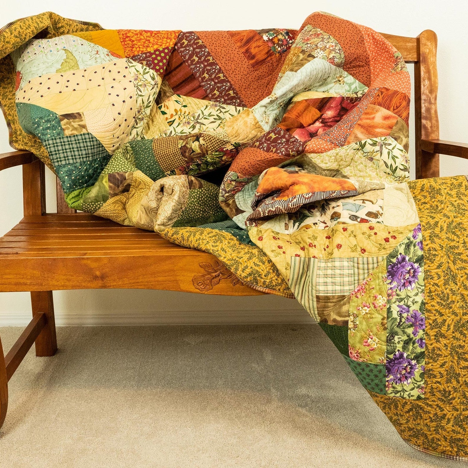 A colorful patchwork quilt draped over a wooden bench in a home setting.