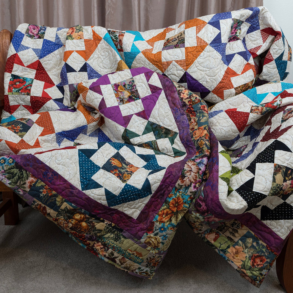 A large, multi-patterned quilted patchwork blanket draped over a wooden armchair in an indoor setting.