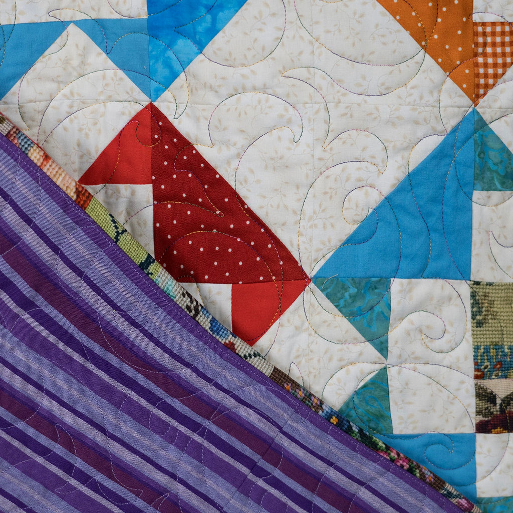 Quilt with geometric pattern and purple fabric draped over it