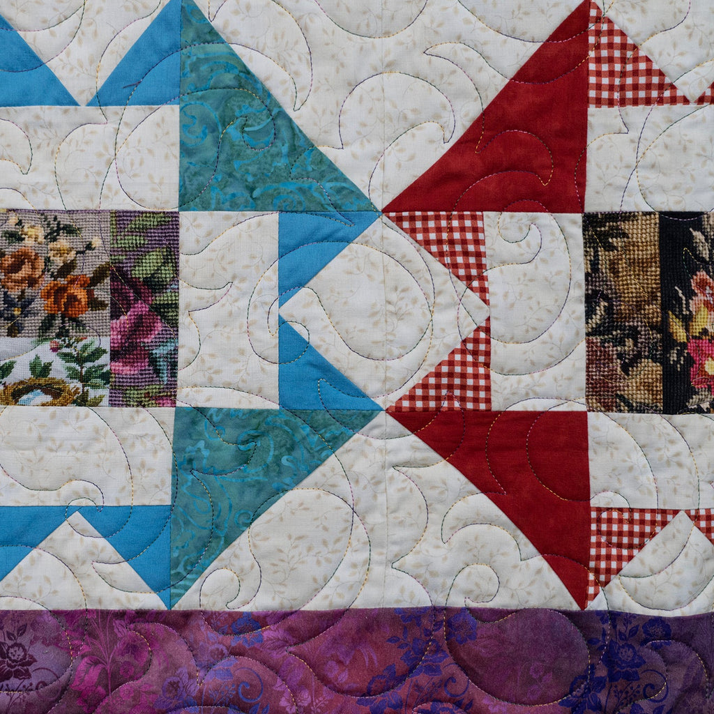 Quilt with a geometric pattern featuring various colors and textures.