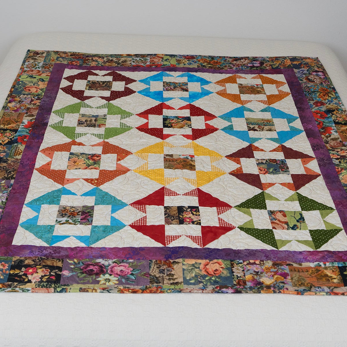 Colorful quilt with geometric pattern on a white bedspread