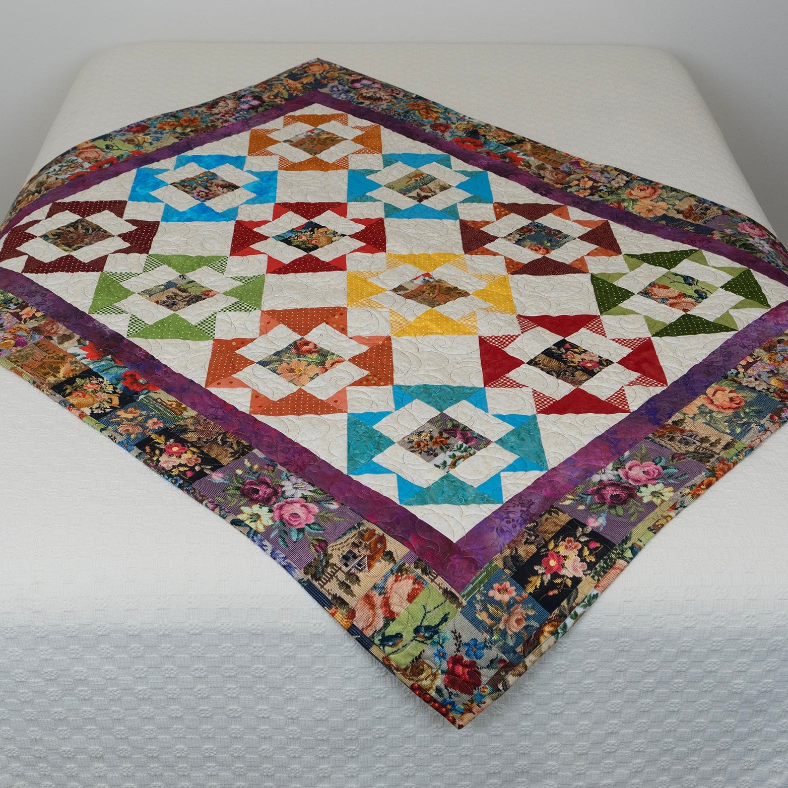 Colorful quilt with geometric pattern on a white bed