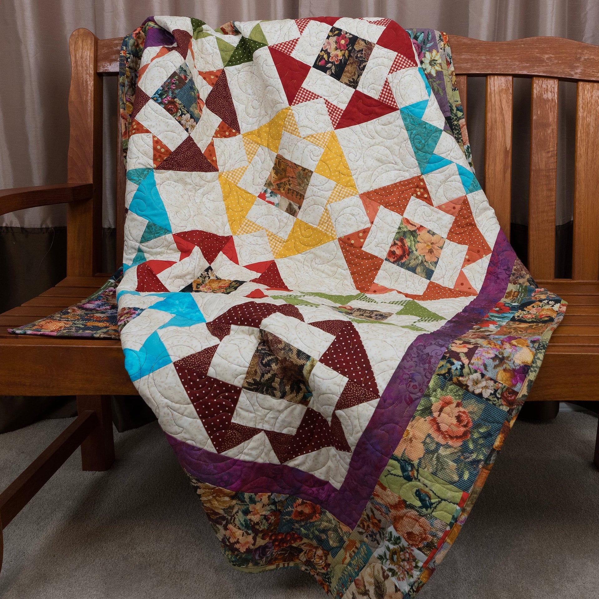Colorful quilt with a patchwork design draped over a wooden chair.