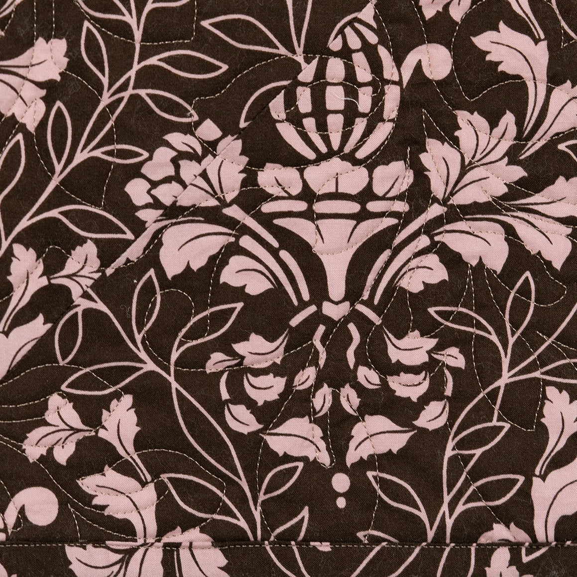 A close-up of a fabric pattern featuring a dark brown background with a light pink damask floral and acanthus leaf design.