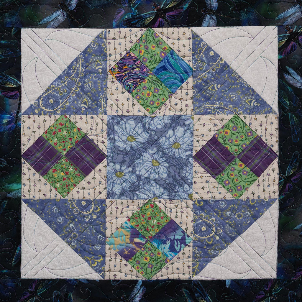 Quilt block with diamond pattern in blue, green, and purple on a dark background